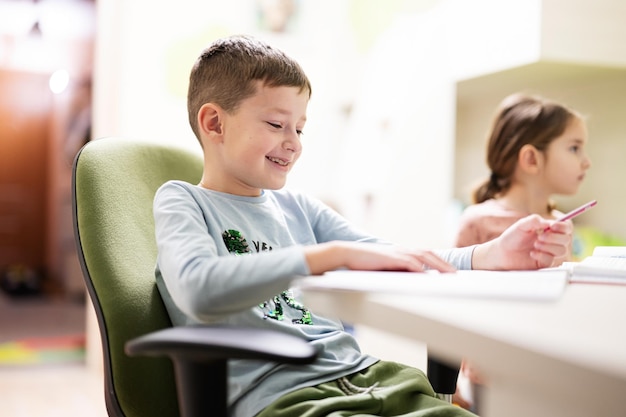 Kid jongen met zus thuis studeren en huiswerk maken op afstand leren onderwijs zittend aan tafel