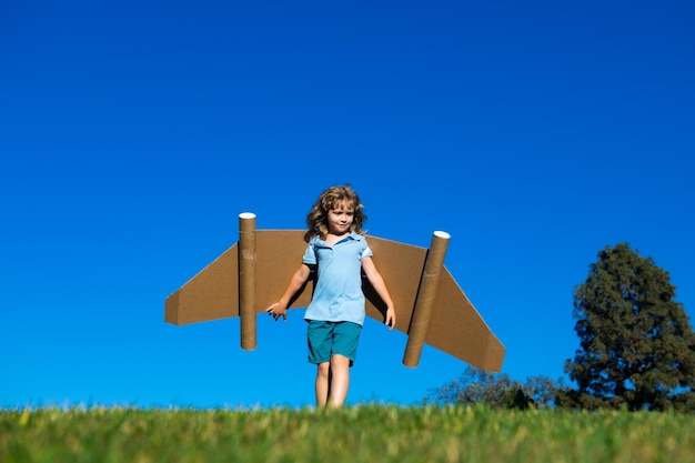 Kid jongen verbeelding kleine piloot droom en vlieg op jetpack vleugels gelukkig kind spelen met speelgoed jetpack