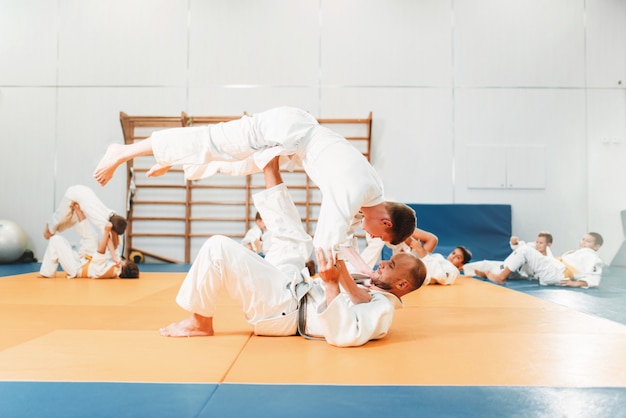 꼬마 유도, 훈련중인 젊은 선수들. 기모노를 입은 어린 소년은 스포츠 홀에서 무술을 연습합니다.