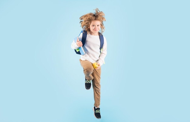 Kid jump and enjoy school full length body of little school kid jumping having fun isolated blue