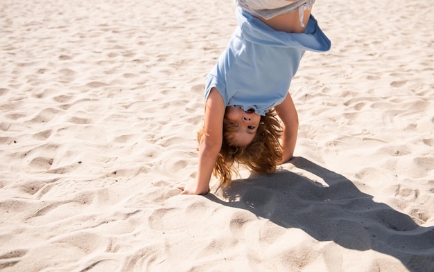 Kid jumping upside down on sand outdoor closeup portrait of funny kids face summer kid outdoor portr