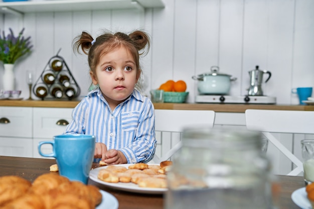 The kid in the kitchen wants to eat cookies with tea at home