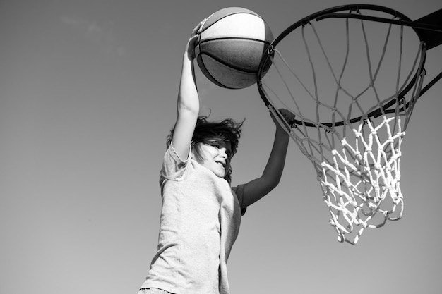 Kid kleine jongen basketbalspeler die slam dunk maakt tijdens basketbalspel