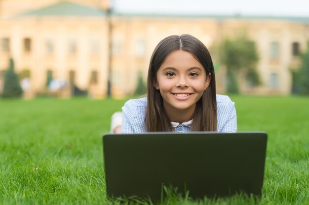 Kid learning private lesson. blogging. happy girl sitting on green grass with laptop. Start up. child playing computer game. back to school. education online. knowledge day. Having fun.