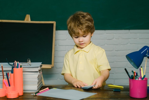 Kid leert in de klas op de achtergrond van schoolbord, kinderen maken zich klaar voor schoolmeisje en jongen met ha