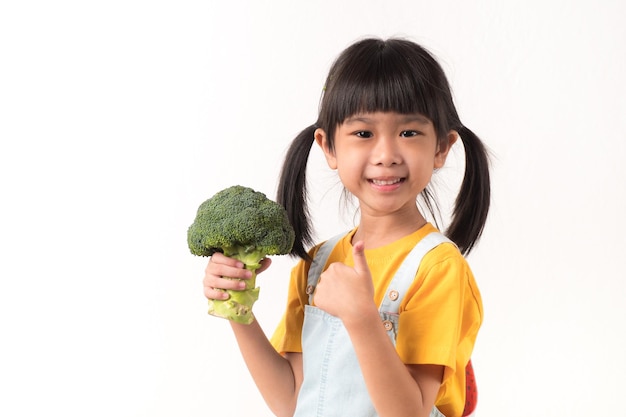 Foto al bambino piacciono le verdure. alla ragazza carina piace mangiare i broccoli.