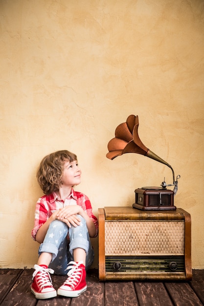 Kid listen music at home. Hipster child with retro vintage radio