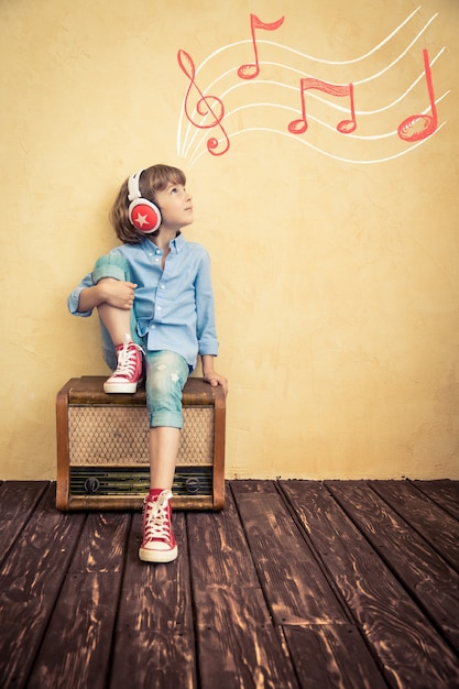 Kid listen music at home. Hipster child with retro vintage radio