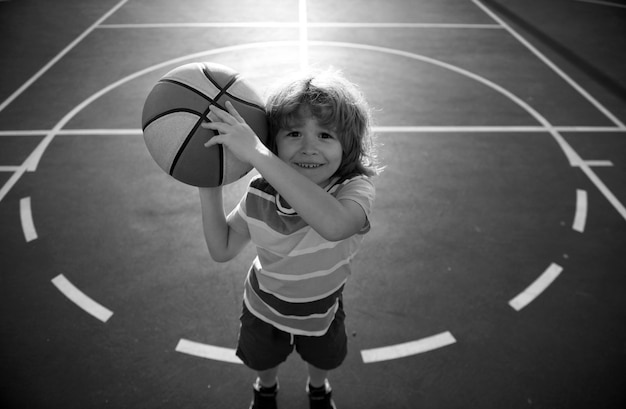 Photo kid little boy playing basketball with basket ball