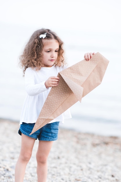 Kid meisje origami papier walvis buiten maken over zee achtergrond