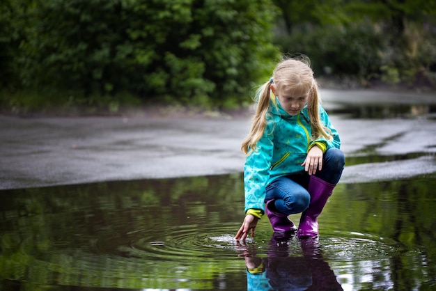 Foto kid meisje speelt in een plas op een regenachtige dag