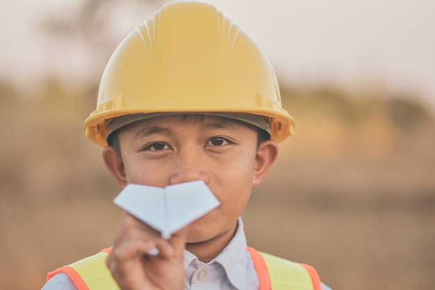 Kid met gele helm en papieren vliegtuigje