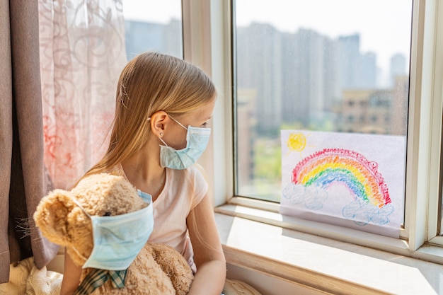 Kid met geschilderde regenboog tijdens Covid-19 quarantaine thuis