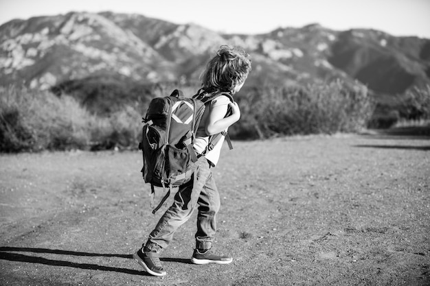 Kid met rugzak wandelen in schilderachtige bergen. Lokale toerist gaat op een lokale wandeling.