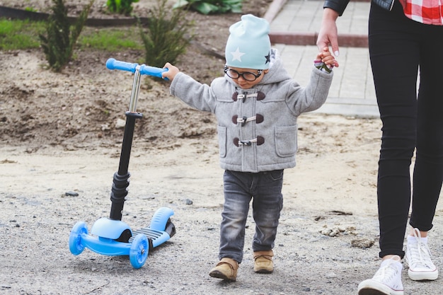 Kid and mom play outdoors with scooter