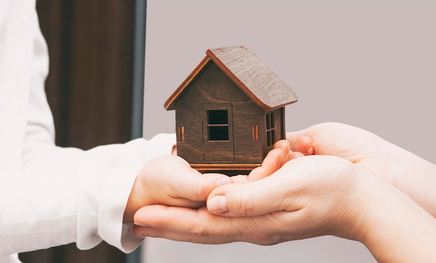 Photo kid and mother hold the wooden toy house adoption concept