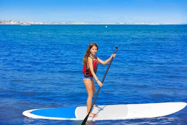 Kid paddle surf surfer meisje met rij in het strand