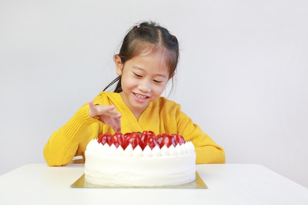 Kid picking strawberries top of cake