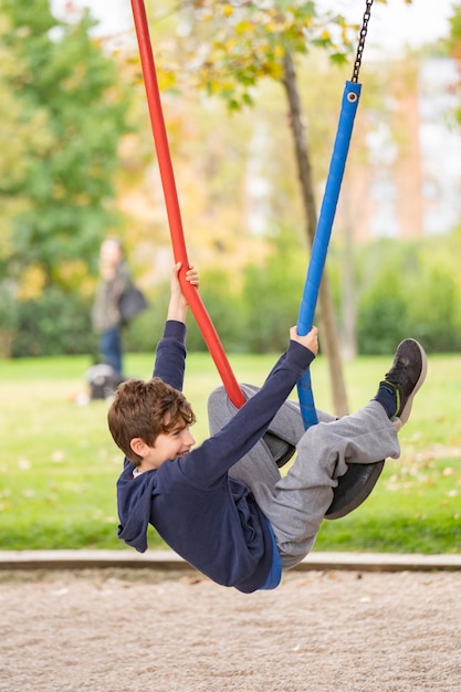 Kid play hanging from steel colourful ropes in a park