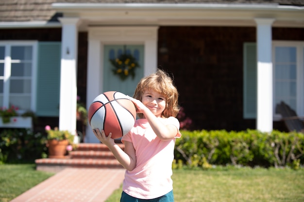 Ребенок играет в баскетбол. Ребенок позирует с баскетбольным мячом снаружи.