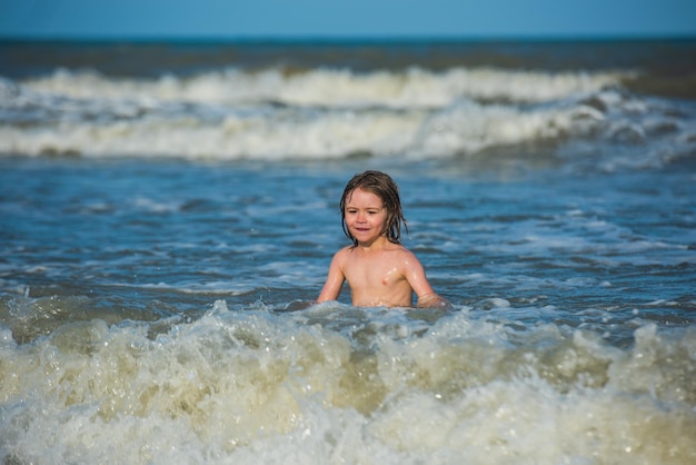 Kid playing on the beach on summer holidays kid swimming in sea with wawes