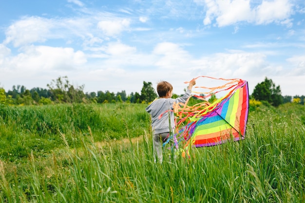 Photo kid playing colorful kite outdoor at summer meadow or park