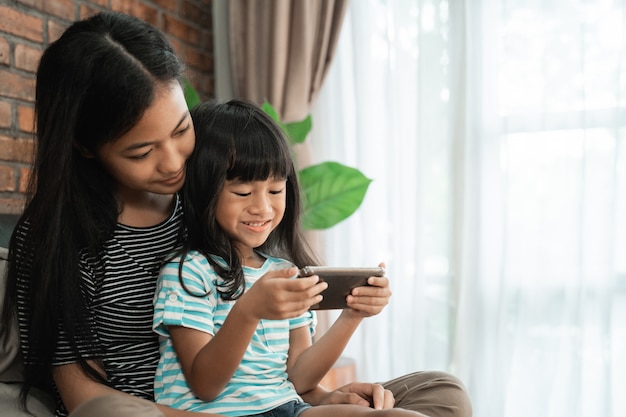 Kid playing game with sister on smart phone