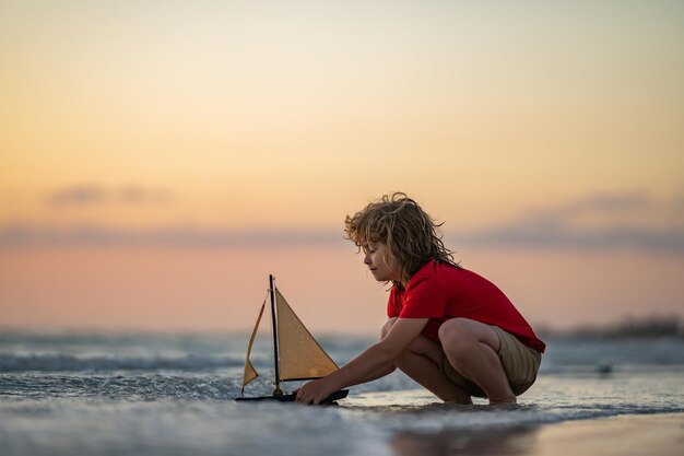 写真 ビーチで遊ぶ子供 おもちゃの船ボートで海で遊ぶ子供 幸せな瞬間を持つ小さな子供