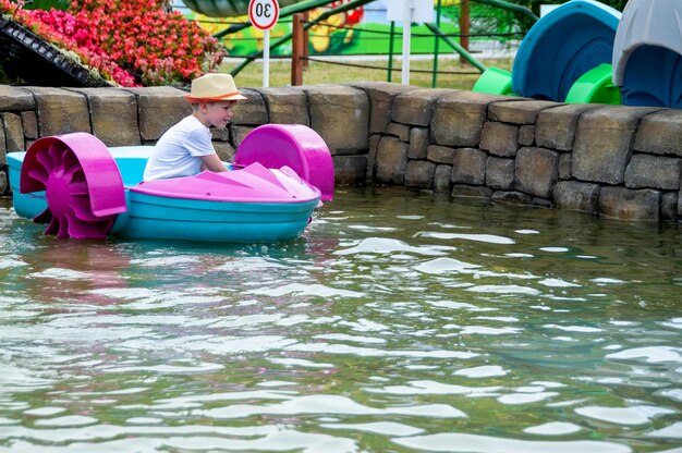 Ragazzo che gioca a remare una barca a remi. focalizzazione morbida una ragazzina guida una barca colorata su una piscina in una località turistica foto di alta qualità