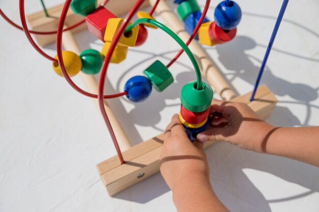 自宅で教育玩具で遊ぶ子供。子供向けのゲームを開発している小さな子供。カラフルなおもちゃを遊んで幸せな子。教育玩具。ゲームの開発、環境に優しい木製