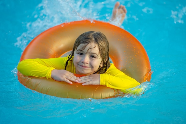 Kid playing with inflatable ring in swimming pool on hot summer day kid with inflatable ring in swim