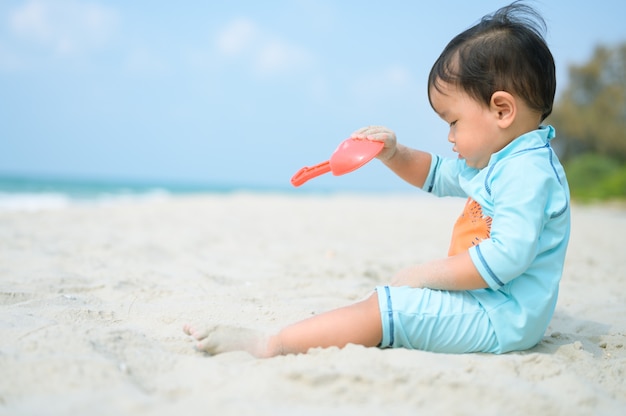 Foto bambino che gioca con la sabbia sulla spiaggia in riva al mare. vacanze con bambini vicino al mare.