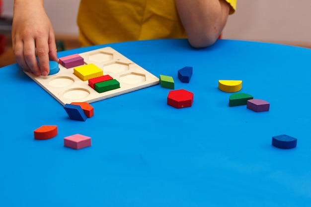 Kid playing with wooden colorful puzzle, education concept