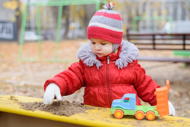 The kid plays cars on the street