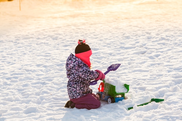 Малыш играет с машиной и лопатой. Концепция очистки города от снега