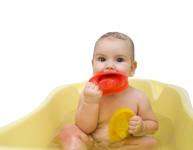 The kid plays with colored boats in the bath Isolated photo of a baby in the bathroom
