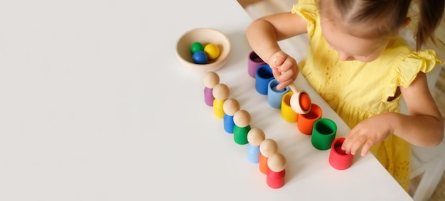 Photo kid plays with an educational toy that helps to learn colors at the kindergarten table