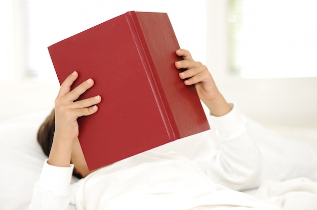 Kid reading book in bed