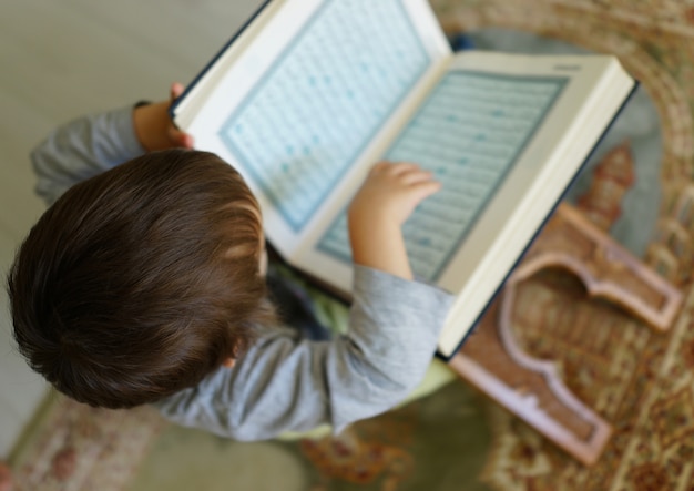 Kid reading Koran (the page is blurred)