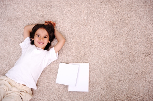 Kid reading for school lying on floor at home