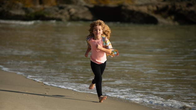 Kid running on beach happy child run in sea on summer vacation little athlete in training runner exe