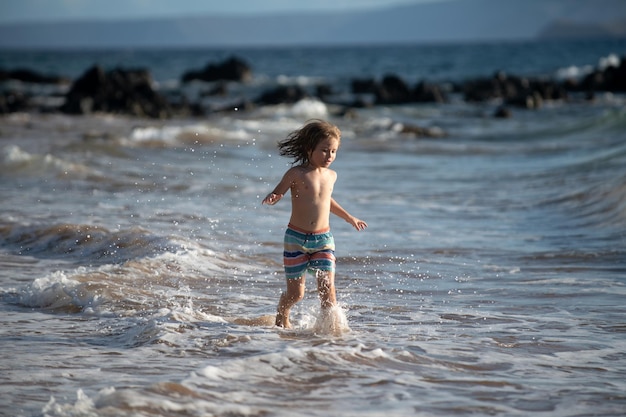 ビーチで走っている子供幸せな子供は夏休みの旅行と海や海での冒険で海で走ります