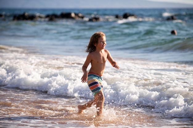 ビーチで走っている子供幸せな子供は夏休みの旅行と海や海での冒険で海で走ります