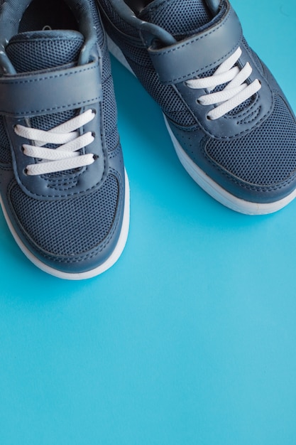 Kid's athletic shoes isolated on blue background.Pair of casual shoes on color background.Sneakers are shoes primarily designed for sports or other forms of physical exercise.Blue shoes.Copy space