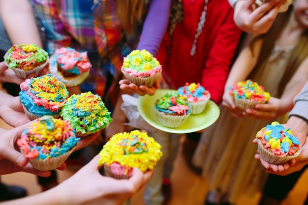 Kid's party. Children holding cupcakes in the glasses.