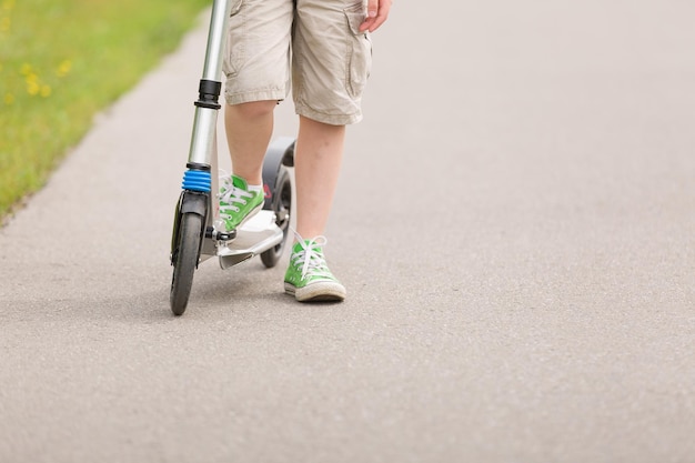 Kid's voeten op scooter Jongen rijdt scooter in het park op zonnige zomerdag lifestyle concept