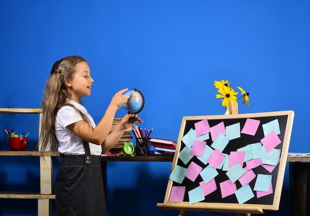 Kid and school supplies on blue wall background