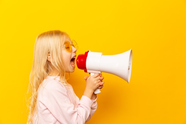 Kid schreeuwen door megafoon. Communicatie concept. gele achtergrond als kopie ruimte voor uw tekst.