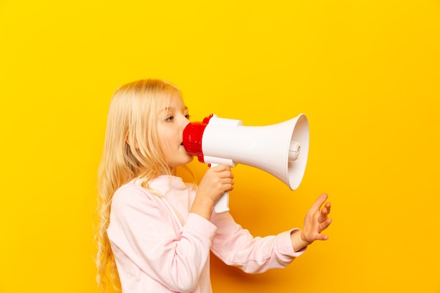 Kid schreeuwen door megafoon. Communicatie concept. gele achtergrond als kopie ruimte voor uw tekst.