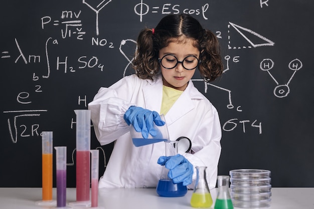 Kid scientist with gloves mixing chemical liquids